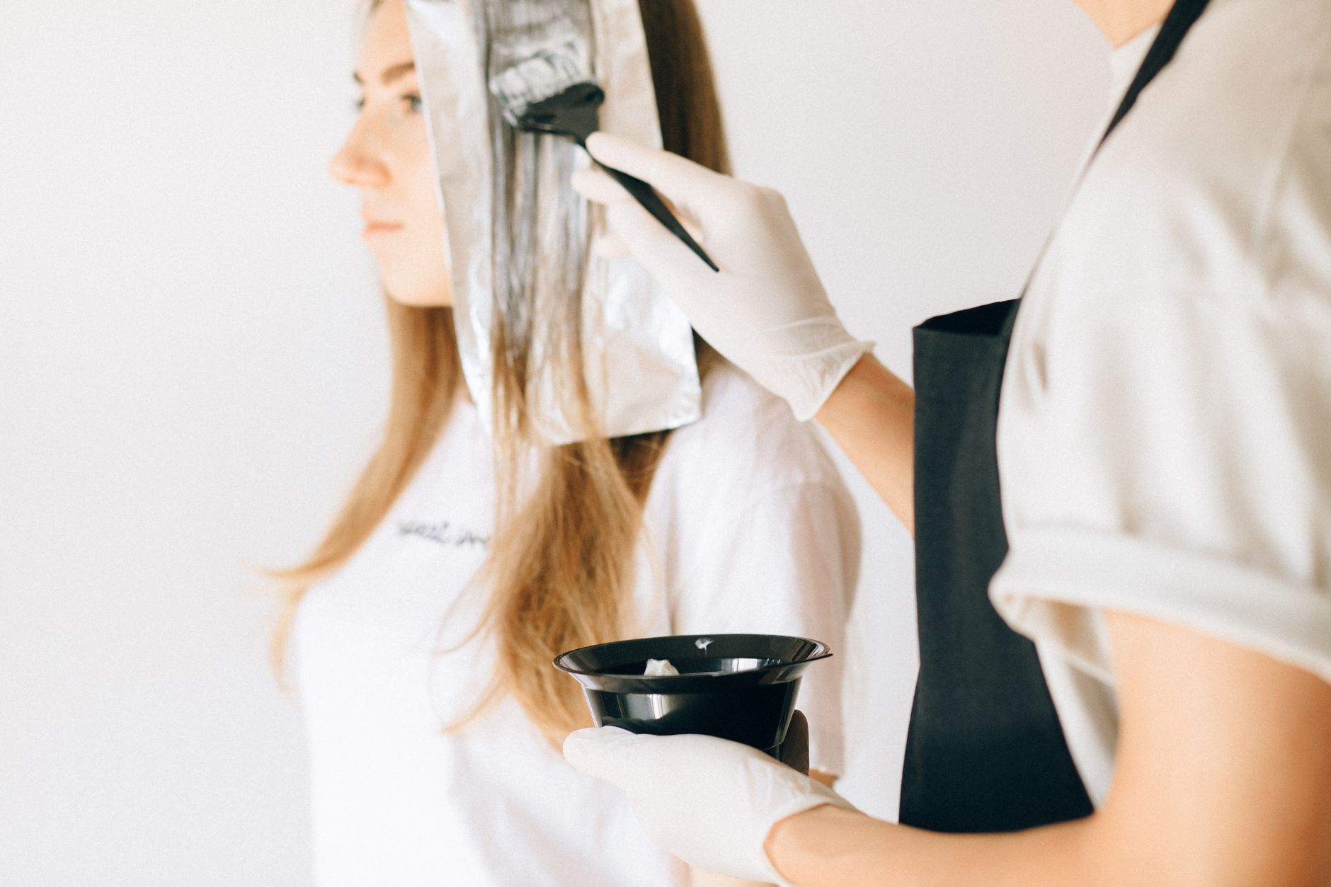 Estilista aplicando color y mechas a una clienta, transformación de look en el salón