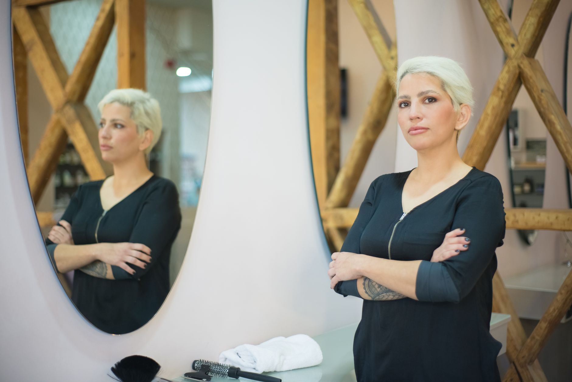 Estilista profesional de pie en un salón moderno, reflejo en el espejo